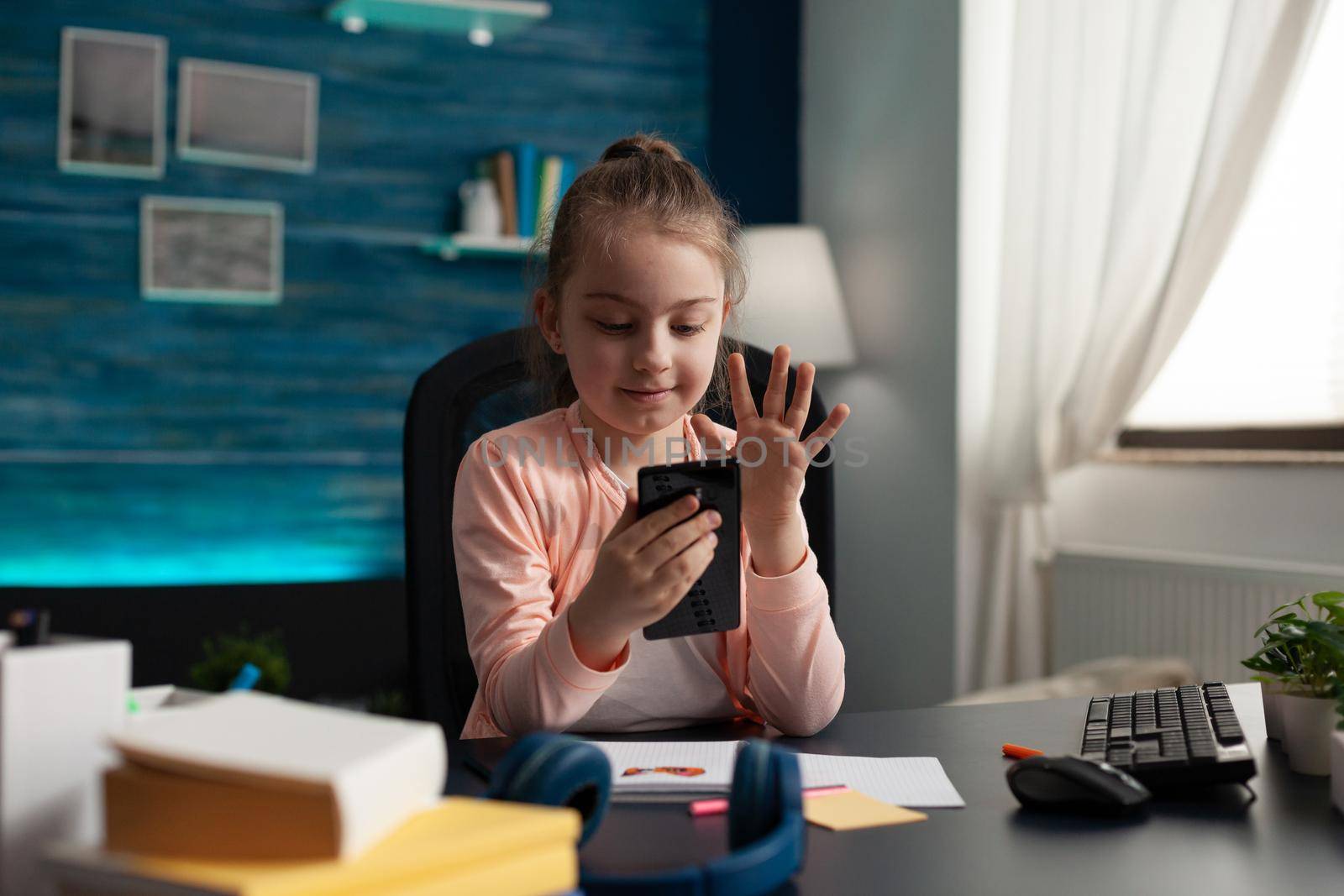 Little student girl using video call on smartphone by DCStudio