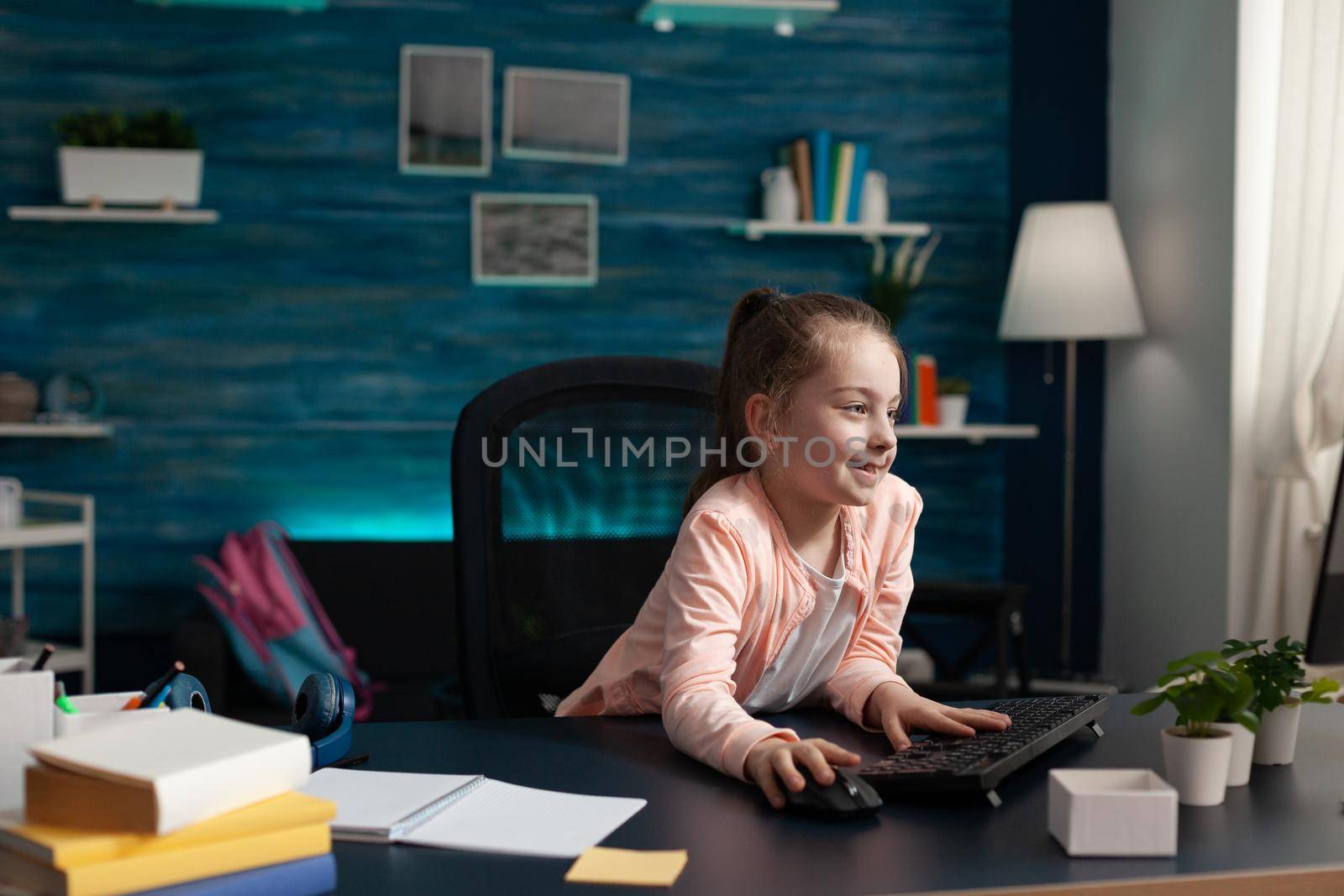 Smart little pupil looking at computer monitor screen at home for online class lesson. Caucasian student paying attention to lecture studying for elementary exam work and knowledge