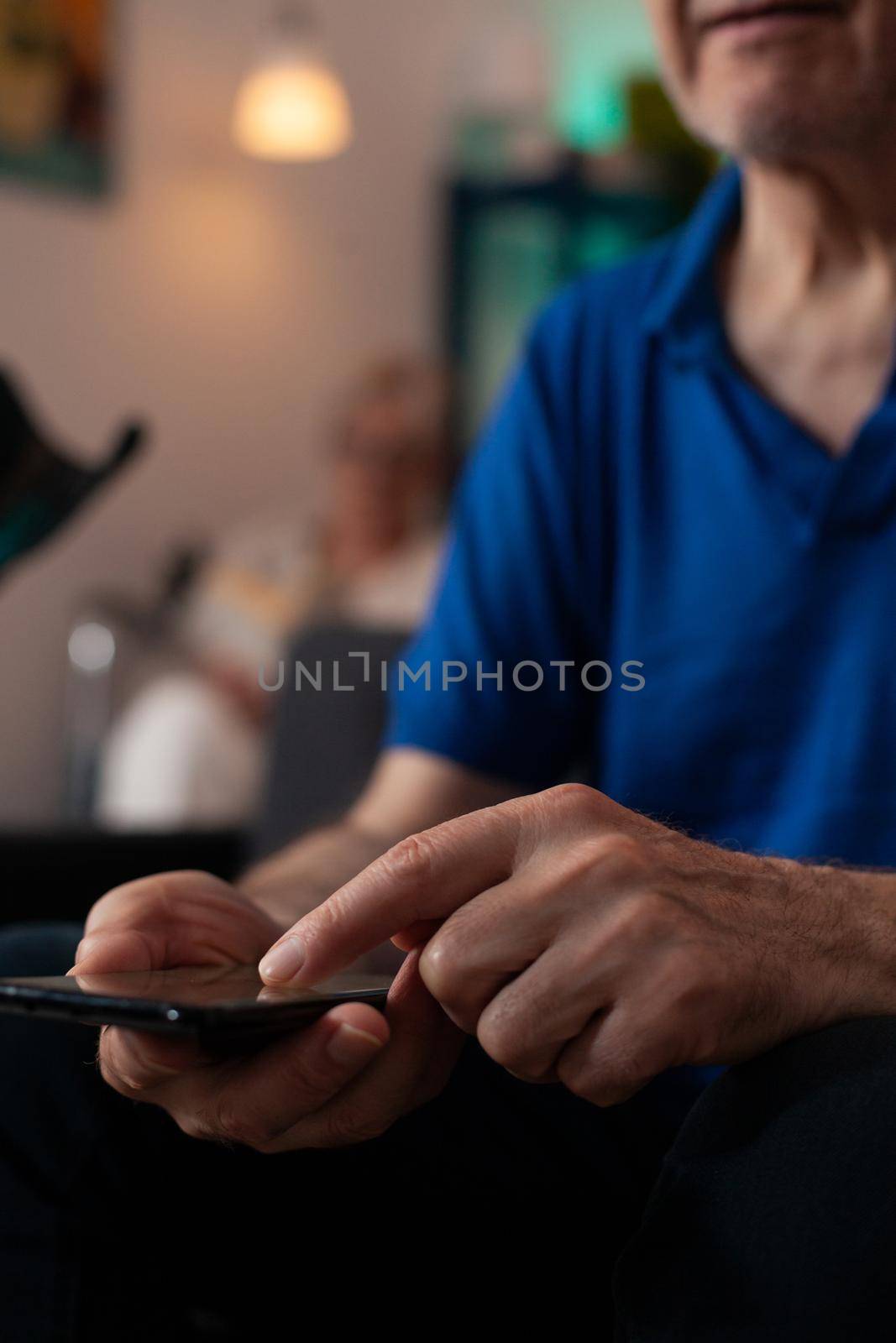 Close up of old mature man hand typing on smartphone screen display using modern technology with online internet connection. Senior person sitting at home learning digital communication