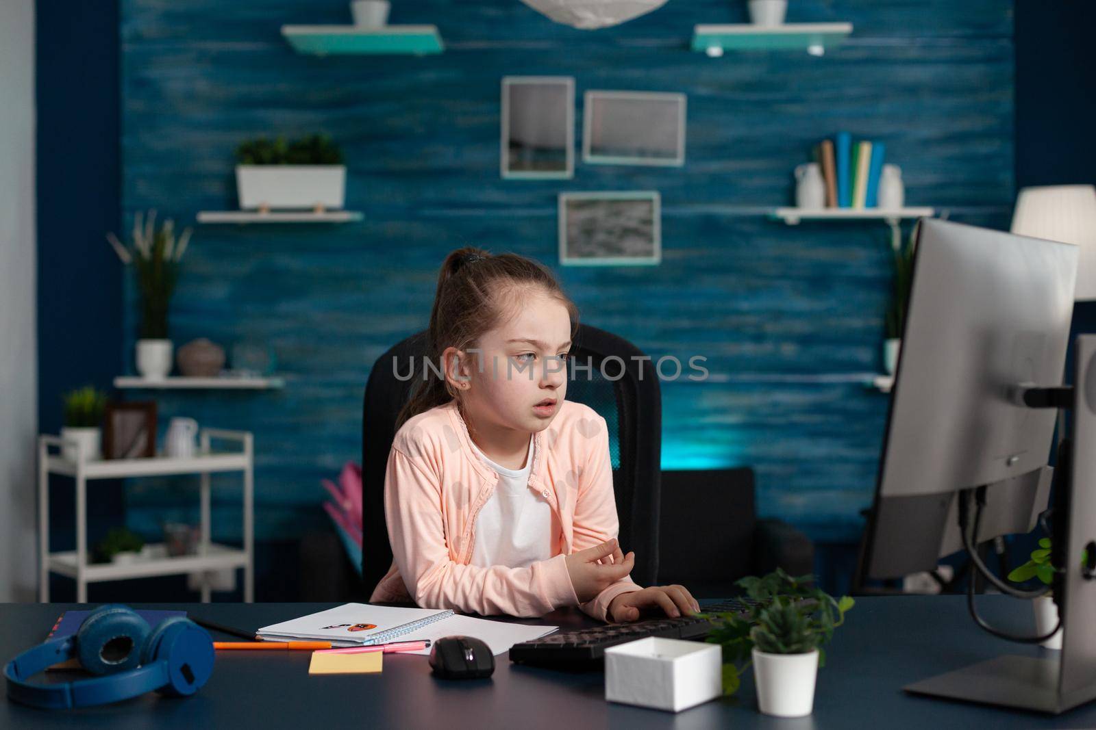 Smart pupil feeling sad and bored of online school classes and lessons at home. Portrait of stressed child doing homework for elementary educational knowledge in internet classroom