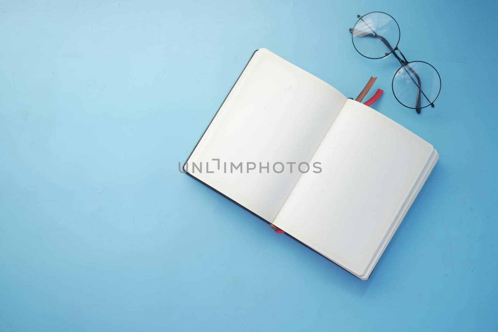 notepad, eyeglass and a pencil on wooden table .