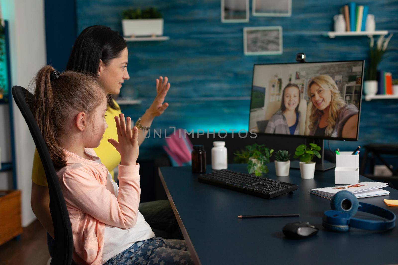 Caucasian family waving at webcam using video call technology online conference communication on internet. Mother and little kid talking to friends on modern computer monitor website app
