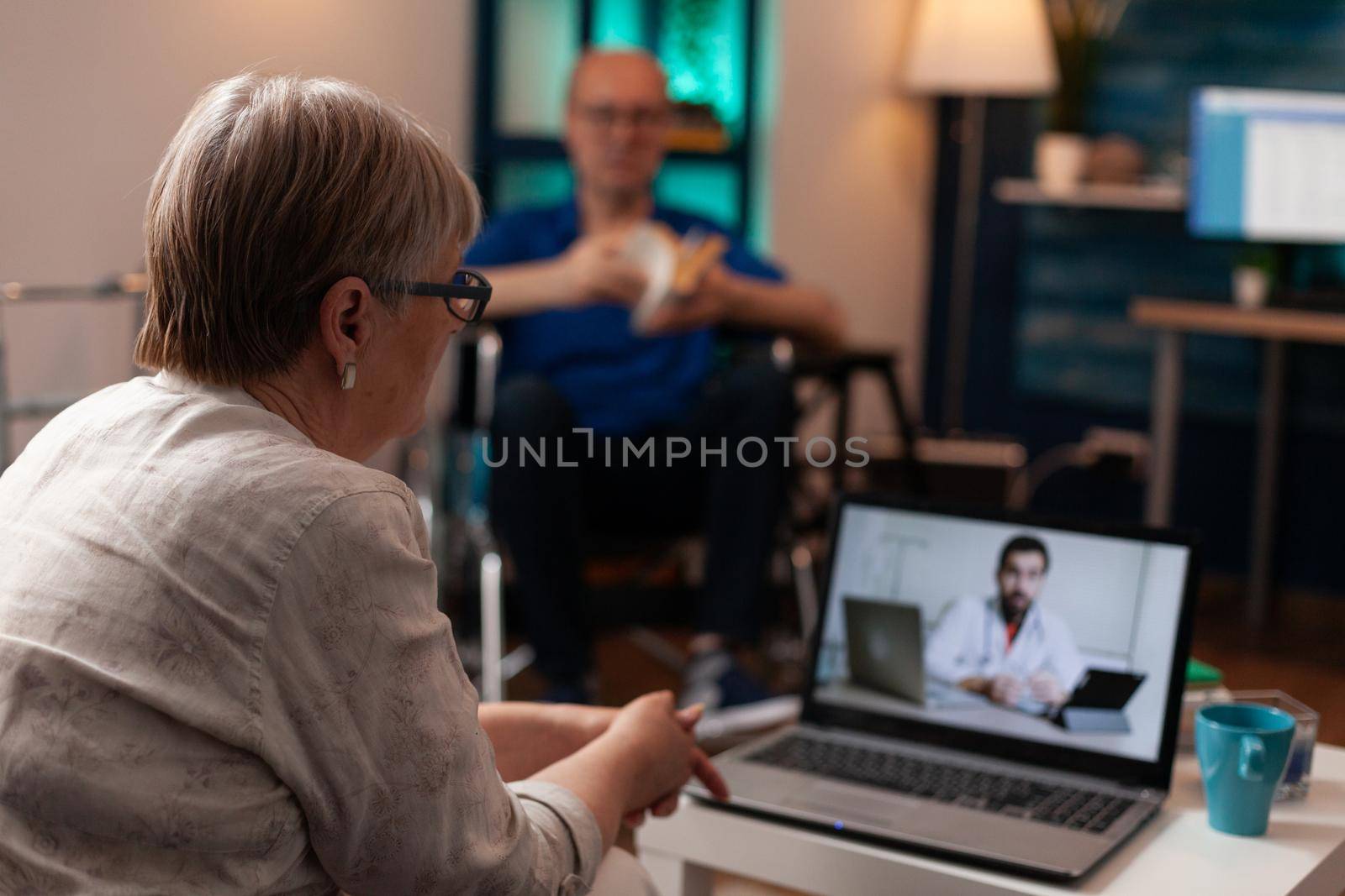 Elder unwell woman calling doctor at clinic using video call conference via online internet sitting at home. Person with laptop asking advice for treatment medicine and pills for teleheath