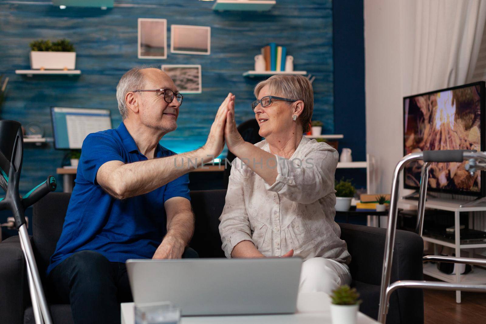 Old aged married couple high five using laptop computer by DCStudio