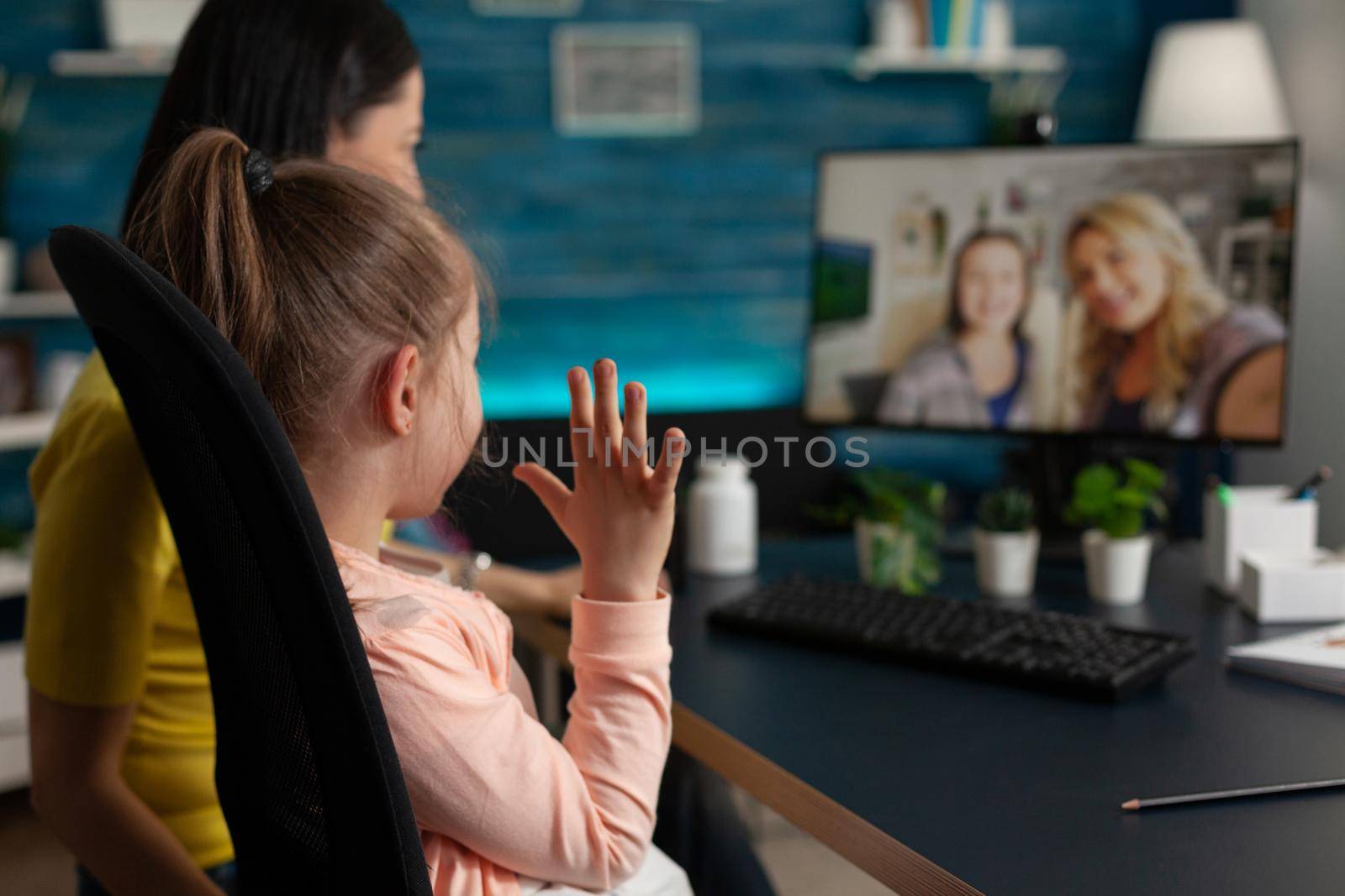 Caucasian family waving at webcam using video call technology online conference communication on internet. Mother and little kid talking to friends on modern computer monitor website app