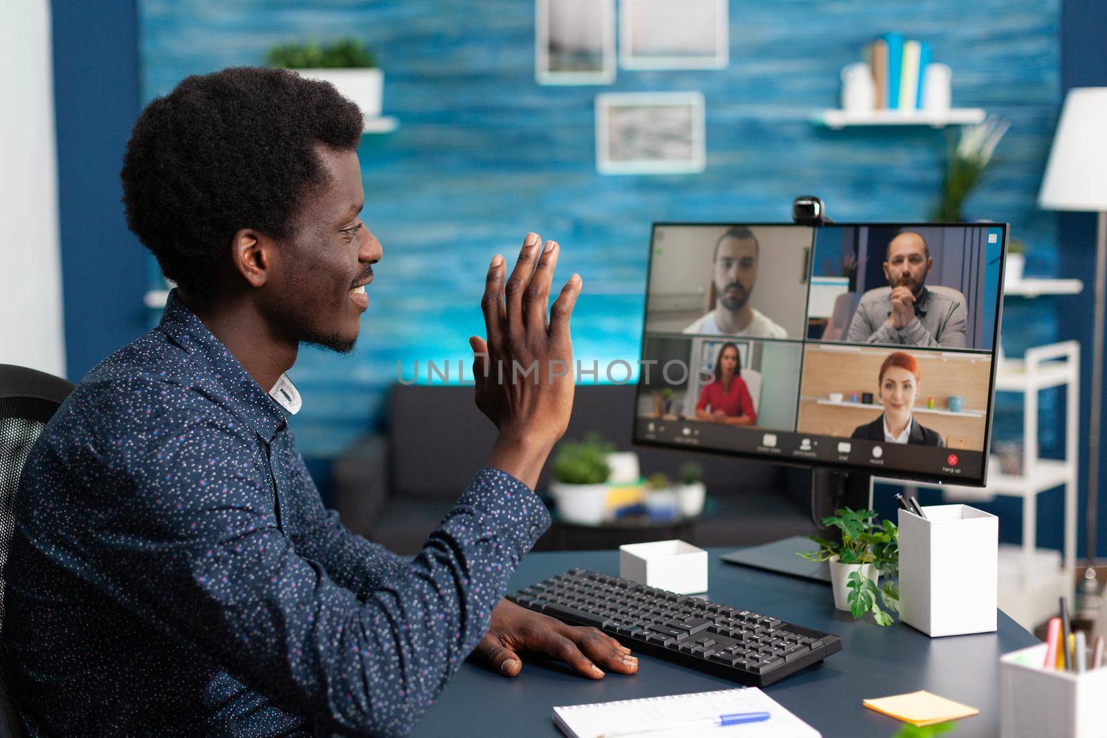 African american man on online conference video call with workmates using webcam communication. Remote internet worker working from home keeping distance while using technology