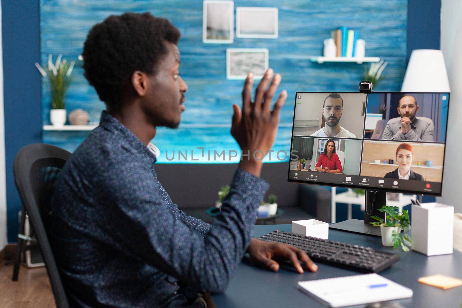 African american man talking on online video call waving to colleagues using webcam communication. Black person working from home keeping distance while using digital technology