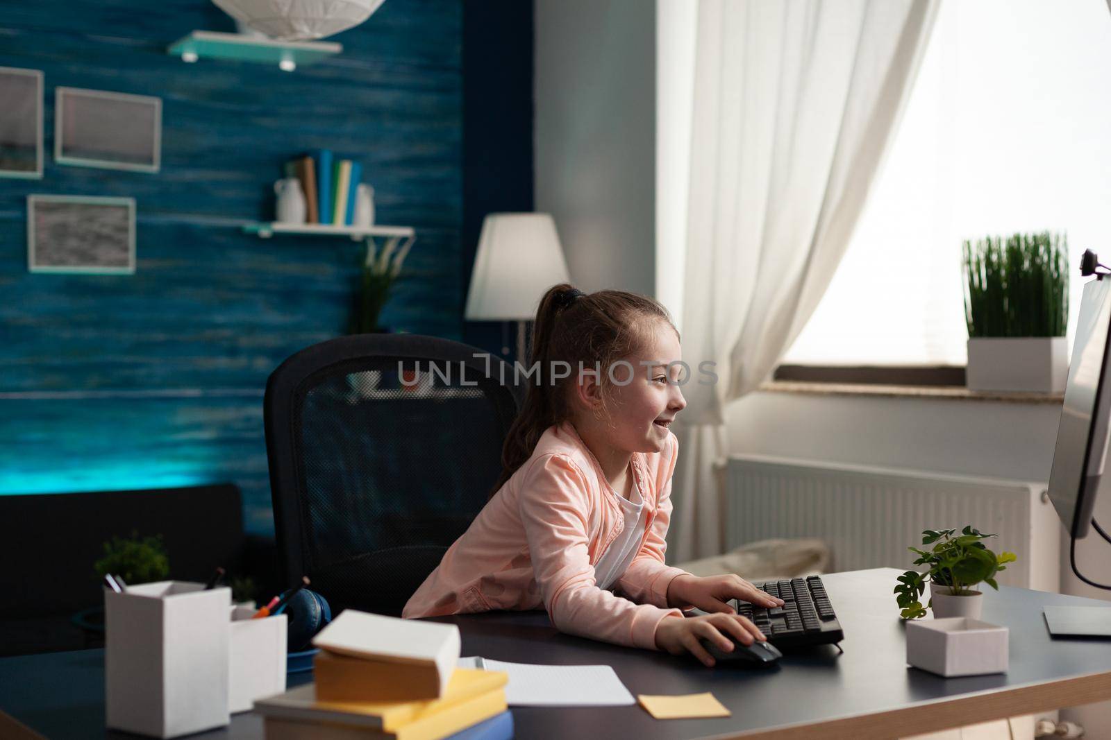 Smart little pupil looking at computer monitor screen at home for online class lesson. Caucasian student paying attention to lecture studying for elementary exam work and knowledge