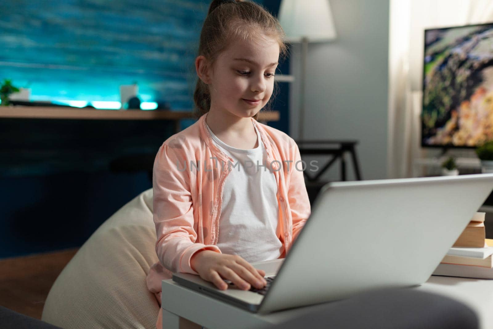 Little school girl using laptop internet technology while sitting at home. Smart student preparing for online class lesson lecture from teacher on knowledge education with modern device