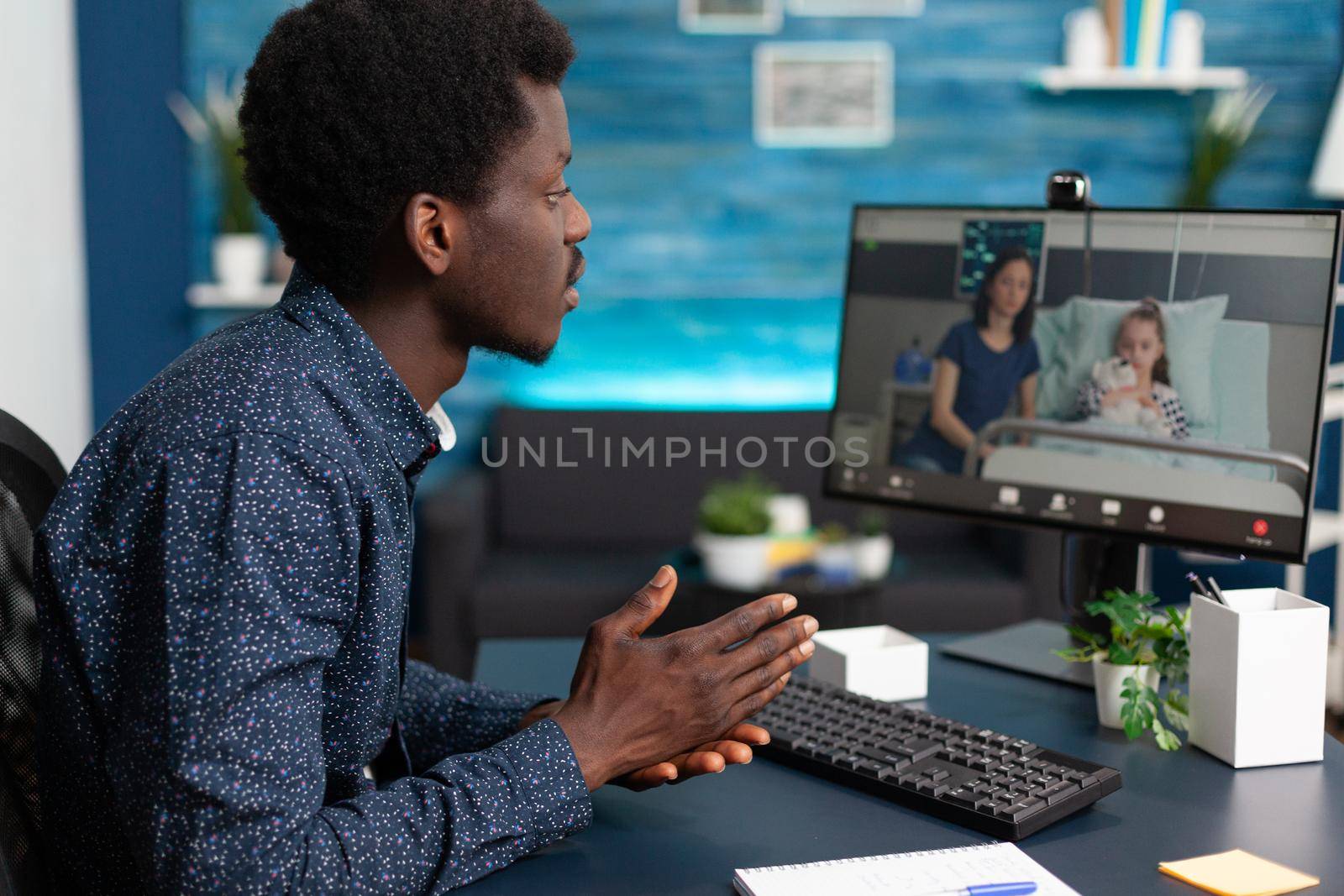 Black man talking with his family in hospital ward, using intenet online teleconference video call to connect with loved ones. Webcam app used for healthcare treatment consultation
