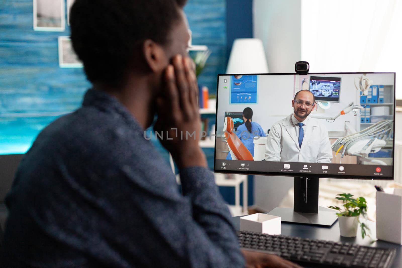 Online health checkup of african american guy talking on video call conference about healthcare sitting at desk. Internet medical consultation of sick patient, virtual telemedicine