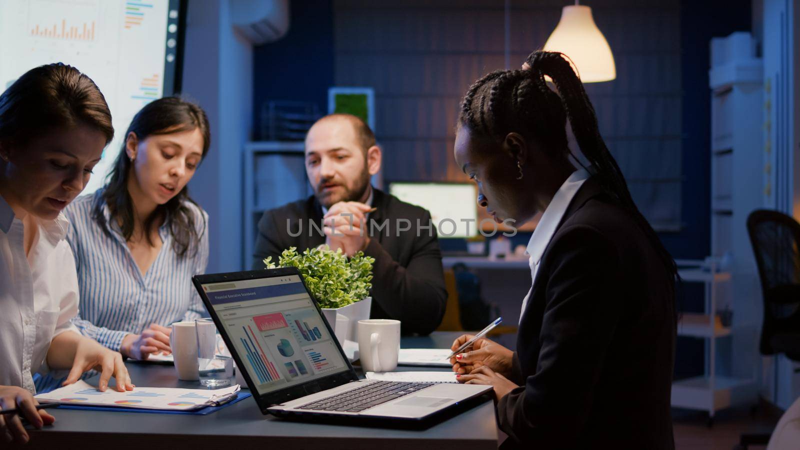 African american businesswoman writing company solution on notebook while diverse teamwork discussing corporate management presentation in meeting room. Multi-ethnic brainstorming strategy ideas