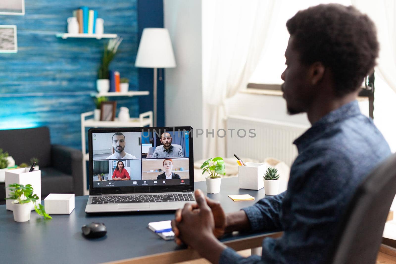 Black man remote employee working from home taking online office call with partners and colleagues. Computer user from desk on video internet conference via webcam conference