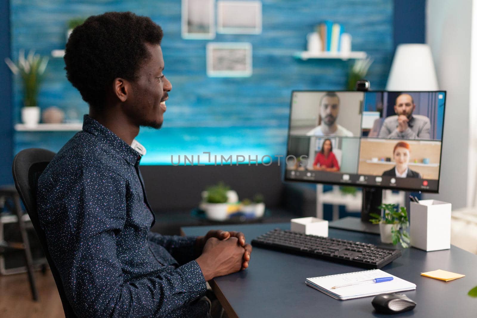 Black man doing online conference video call to talk via internet with colleagues while working from home. African american person remote worker at desk using computer technology