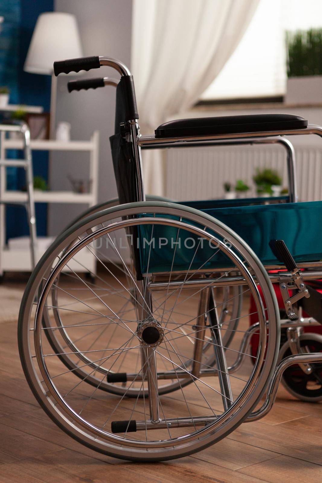 Empty living room with nobody in it prepared for healthcare therapy recovery equipped with medical wheelchair, hospital medicine red bag. Social support nursing services at home