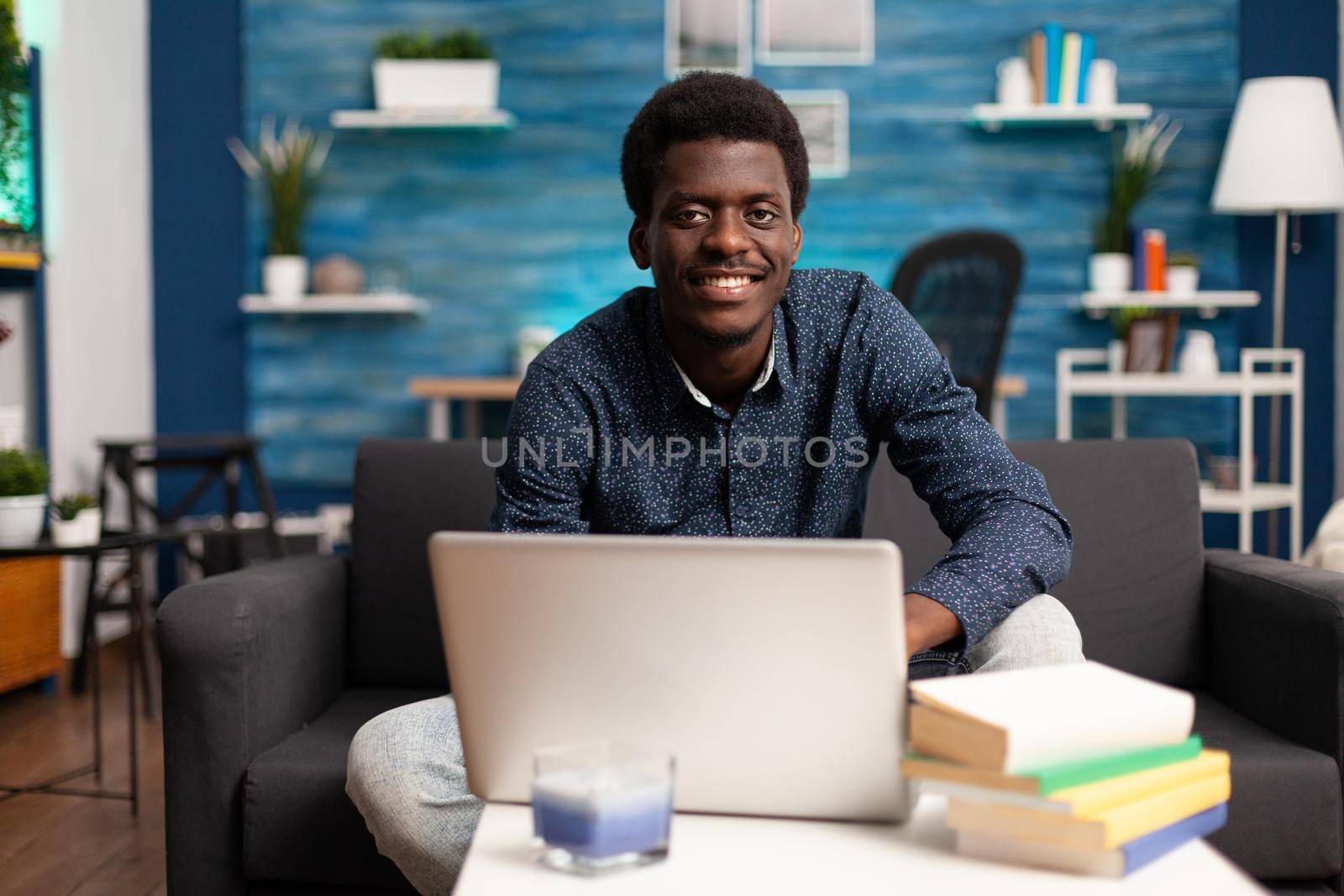 Black entrepreneur on remote online conference from couch. Worker talking with boss about business using internet website online communication app. African american employee on video call