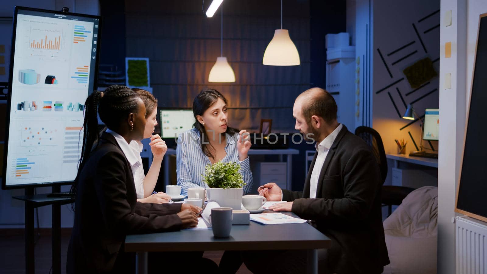 Executive manager woman explaining management statistics working at company strategy overtime in office meeting room. Diverse multi-ethnic businesspeople teamwork brainstorming ideas in evening