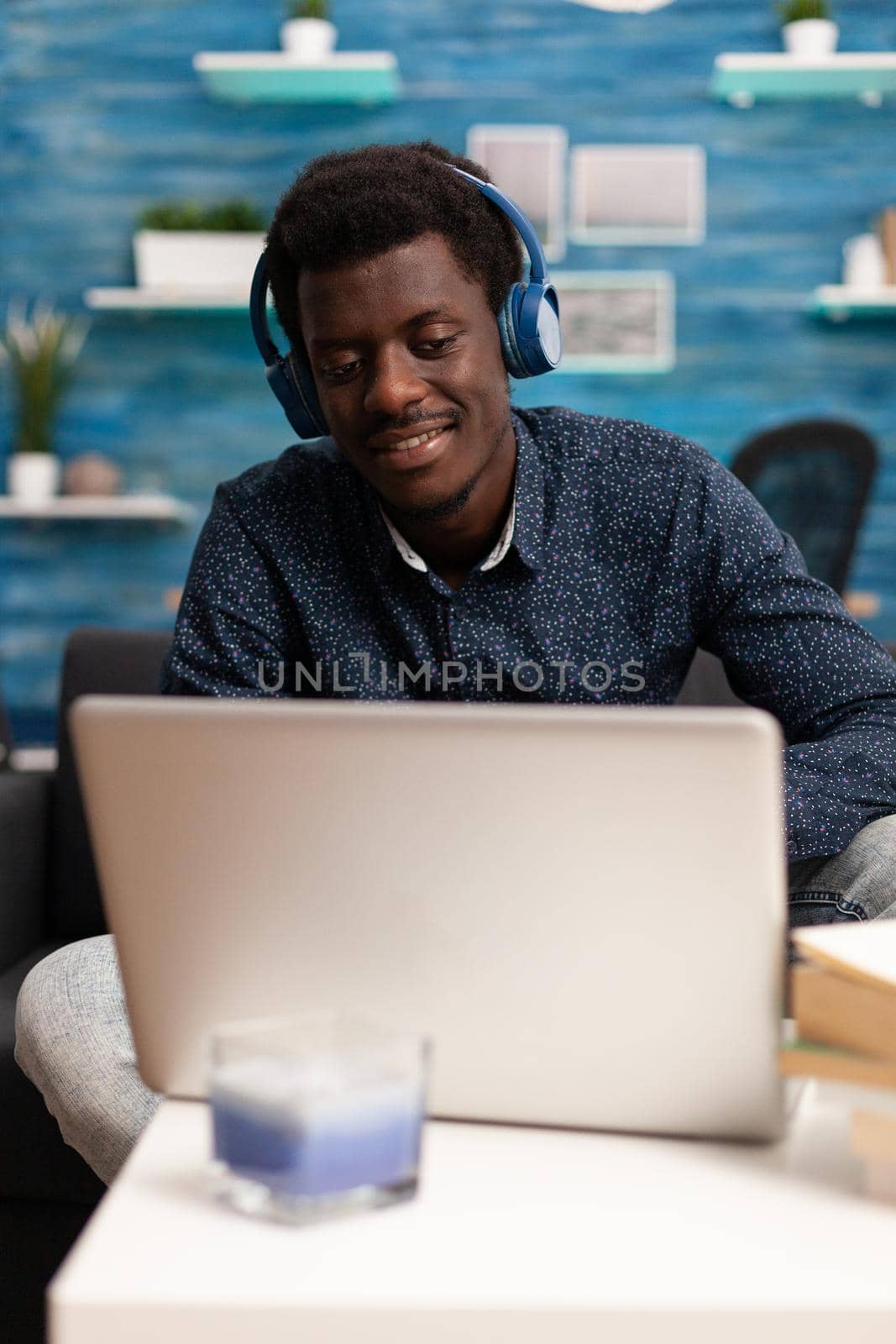 African american man wearing headphones using laptop typing on internet website online services. Working from home black computer user utilizing modern technology and communication devices