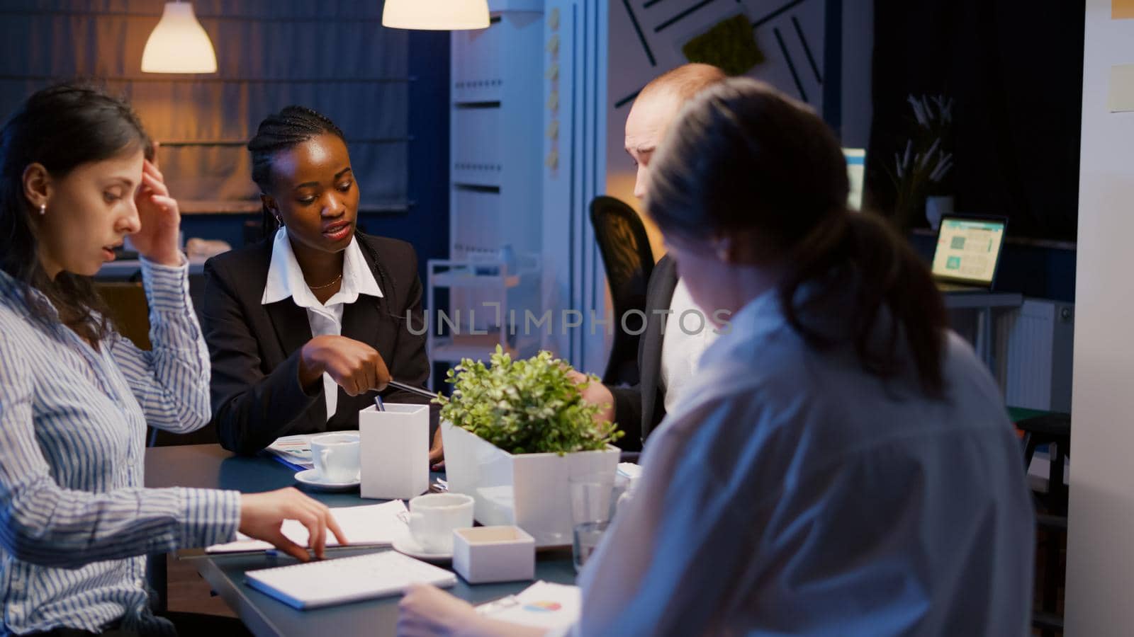 Business diverse multi ethnic entering office meeting room brainstorming company ideas sitting at conference table late at night. Business teamwork analyzing management presentation paperwork