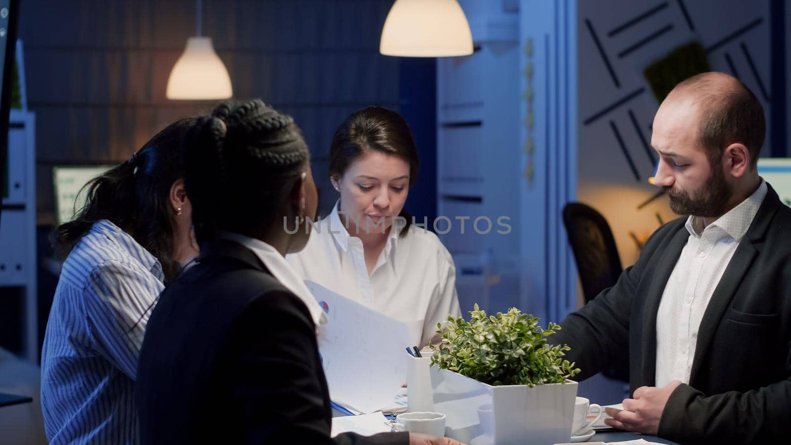 Diverse multi ethnic coworkers working in office meeting room analyzing management graphs by DCStudio