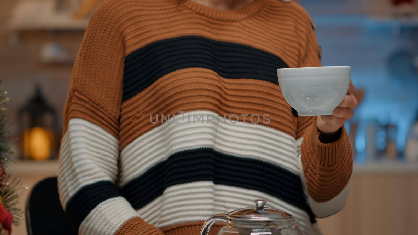 Close up of young adult holding cup of tea in kitchen by DCStudio