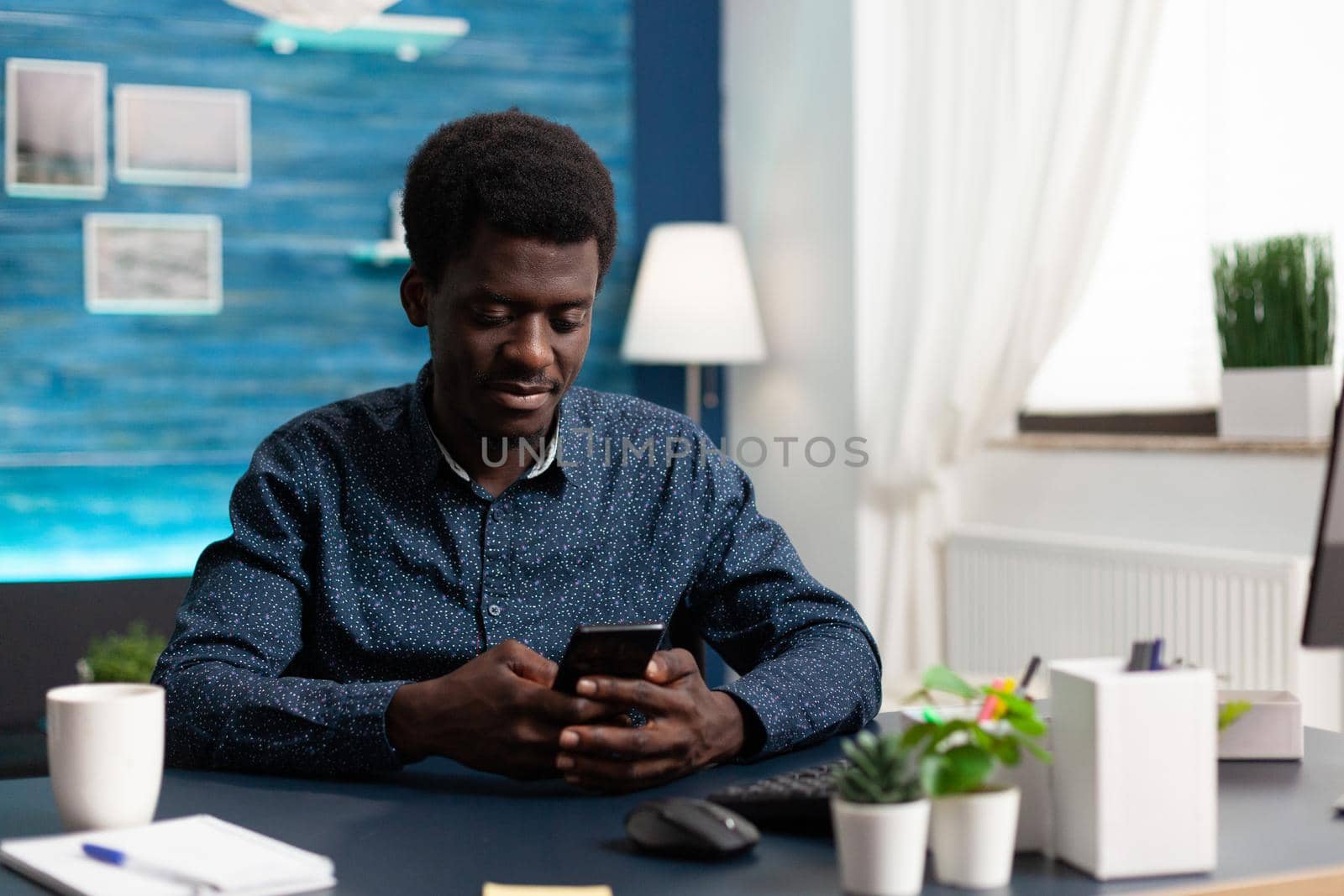 Black african american man using a smartphone at home by DCStudio