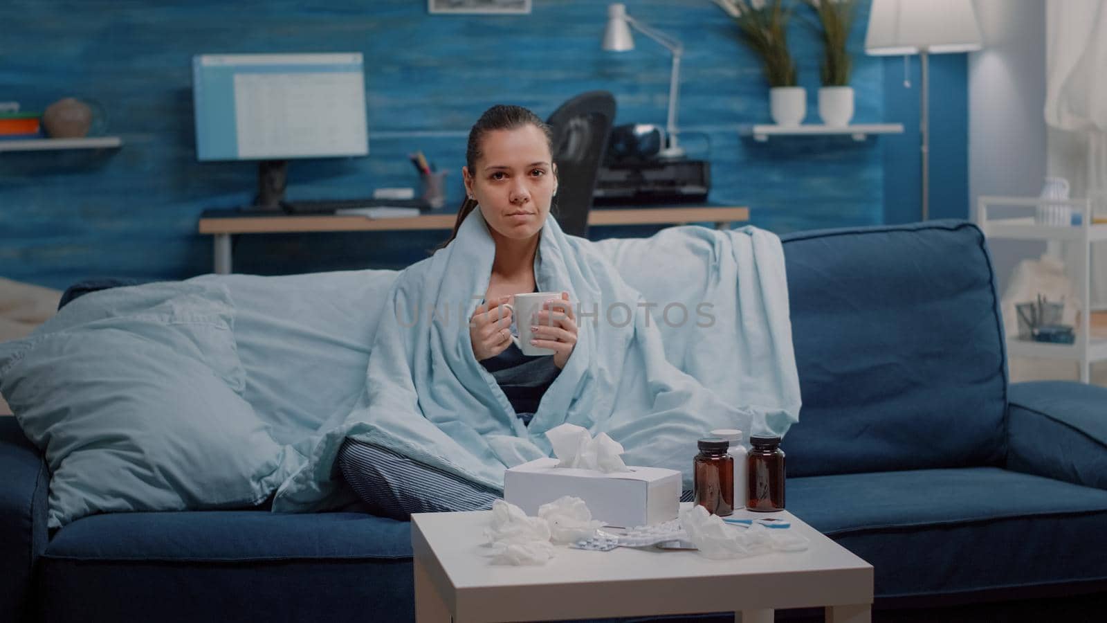 Portrait of woman with flu holding cup of tea in blanket by DCStudio