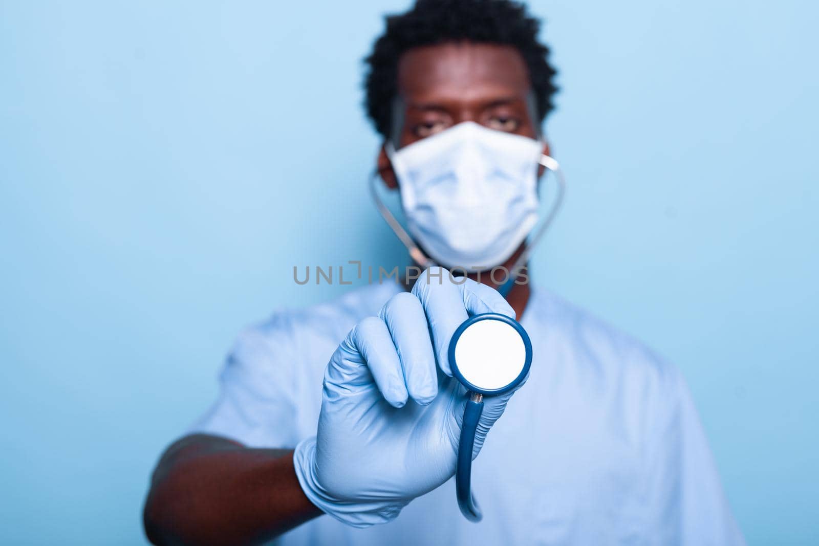 Close up of cardiologist with stethoscope for heartbeat examination in studio. Medical nurse with cardiology instrument wearing face mask and gloves for protection against coronavirus