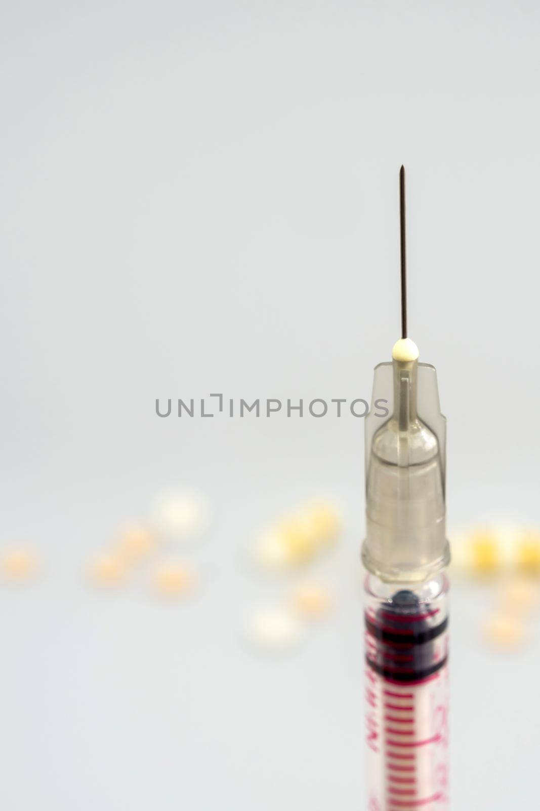 Syringe, injection needle and some pill on white background