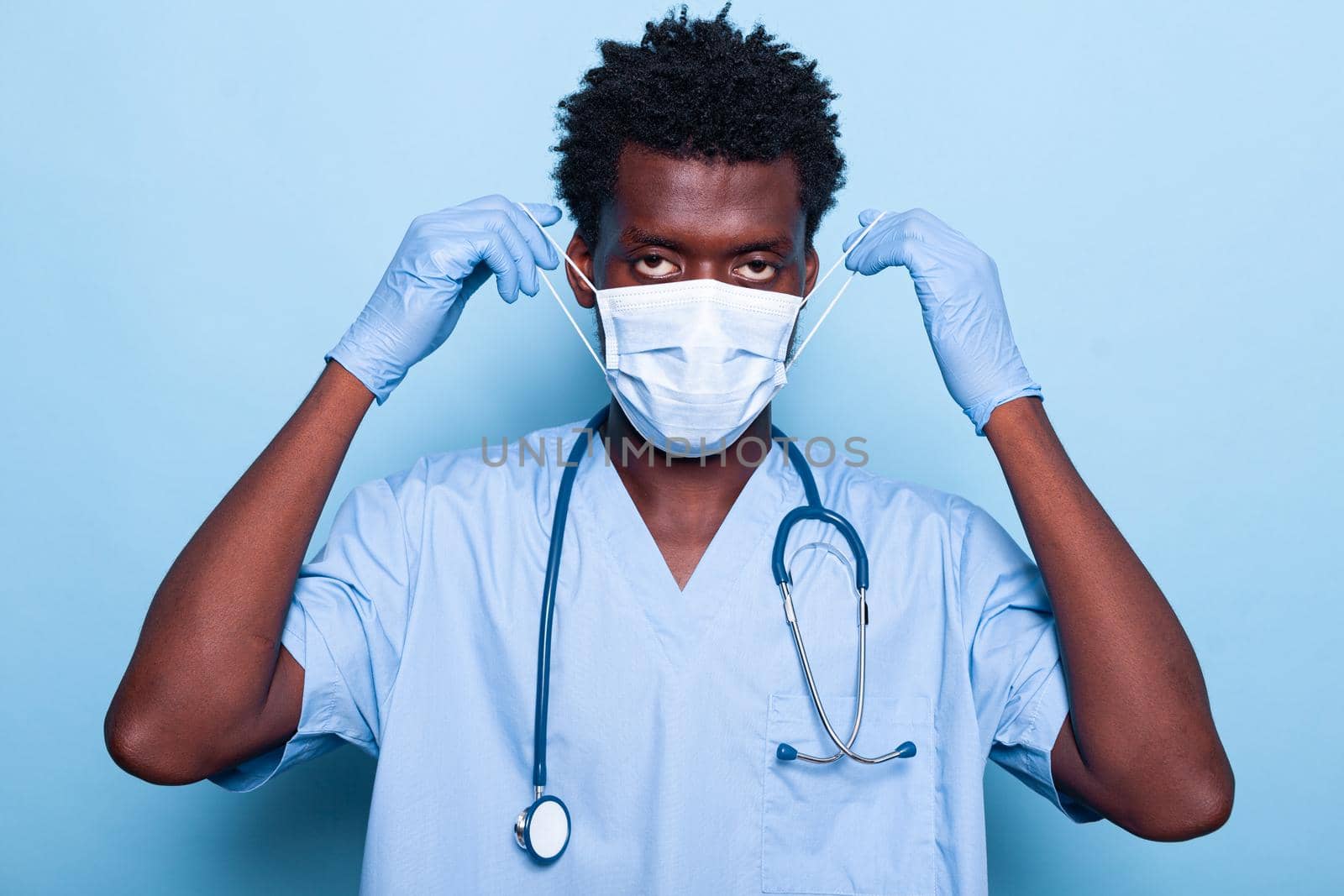 Portrait of medical assistant putting mask on face for protection by DCStudio