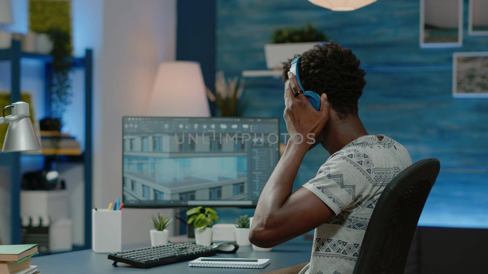 Engineer wearing headphones and designing building model for architectural development. Architect working with skyscraper plan for construction layout. Urban project on computer