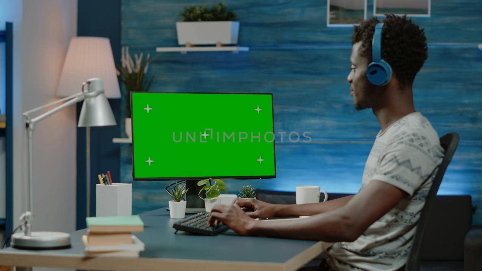 Man looking at horizontal green screen on computer for remote work by DCStudio