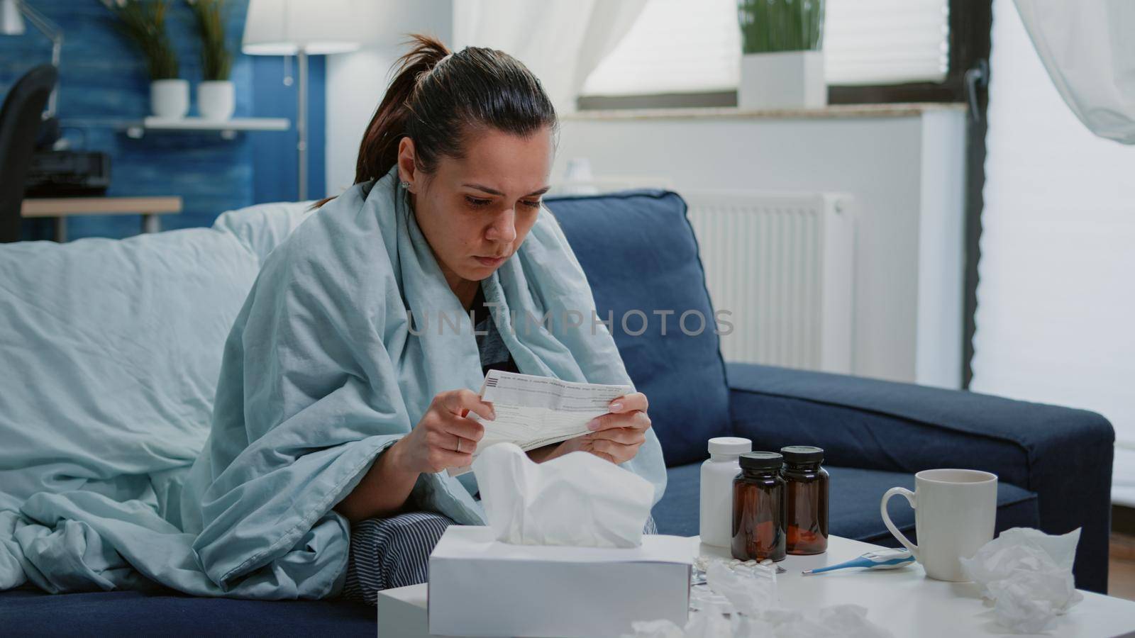 Person with disease infection analyzing package leaflet of pill bottles to cure illness. Woman feeling cold reading medical paper with medication instructions, having medicaments on table