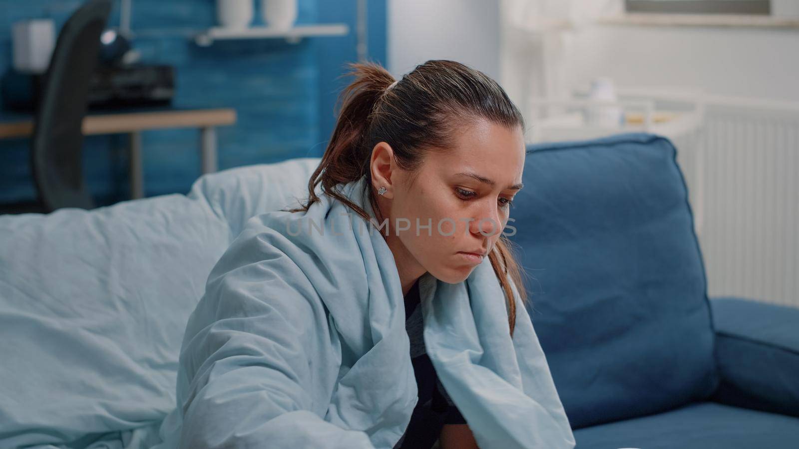 Close up of ill adult looking for medical treatment on table. Sick woman with tablets of medicaments, bottles of pills, box of tissues and thermometer to cure seasonal cold and flu