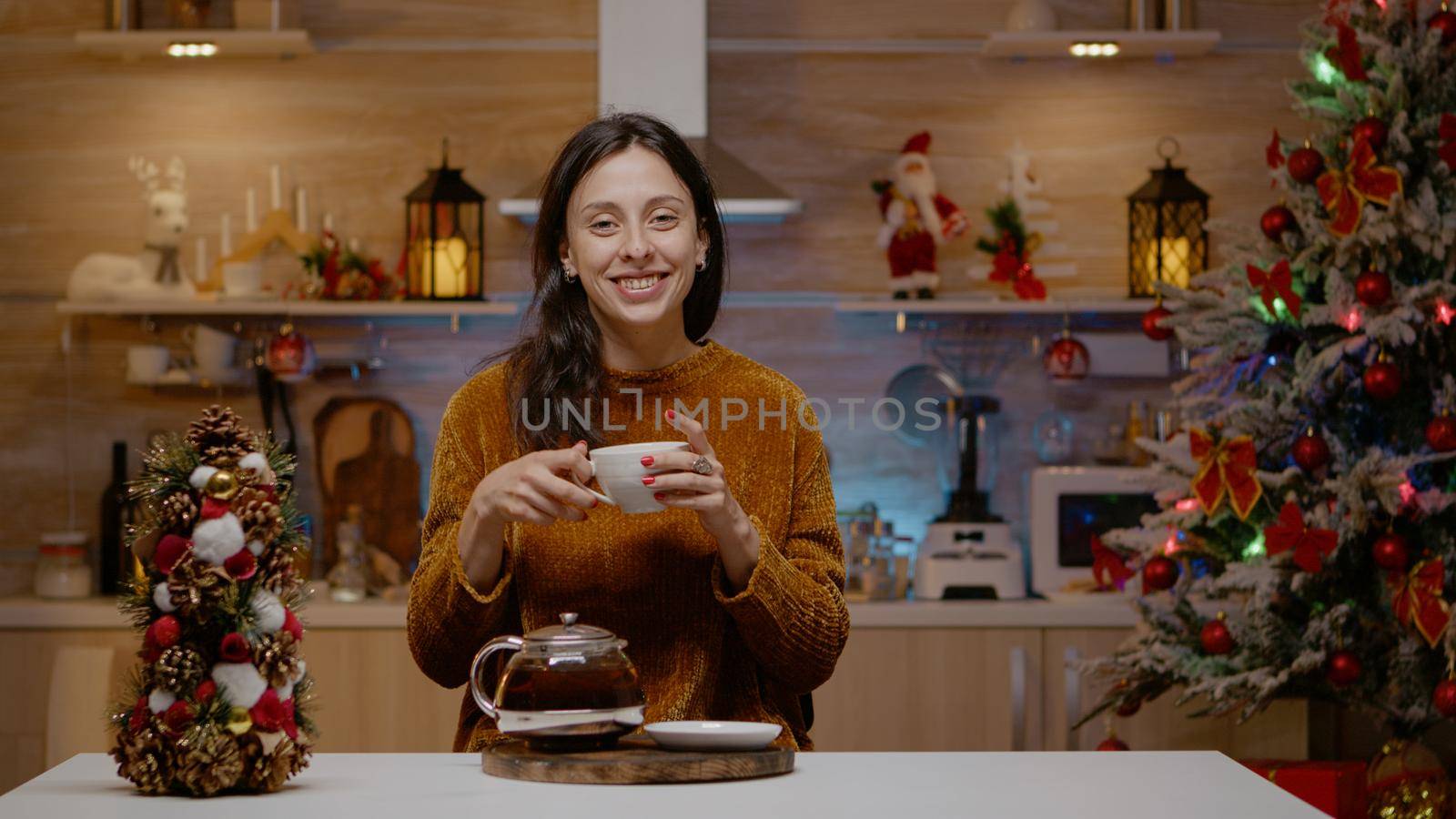 Festive woman talking on video call conference with family in decorated kitchen. Person chatting on online internet communication for christmas celebration on holiday. Merry season