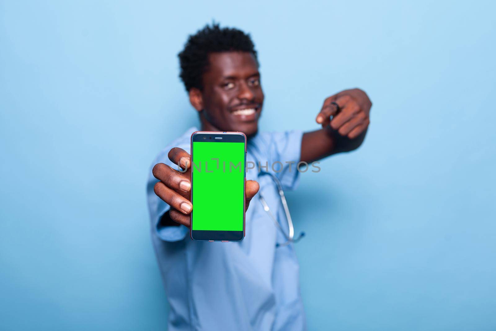 Nurse showing smartphone with vertical green screen. Medical assistant holding device with chroma key and mockup template for isolated background on display. Man with modern phone
