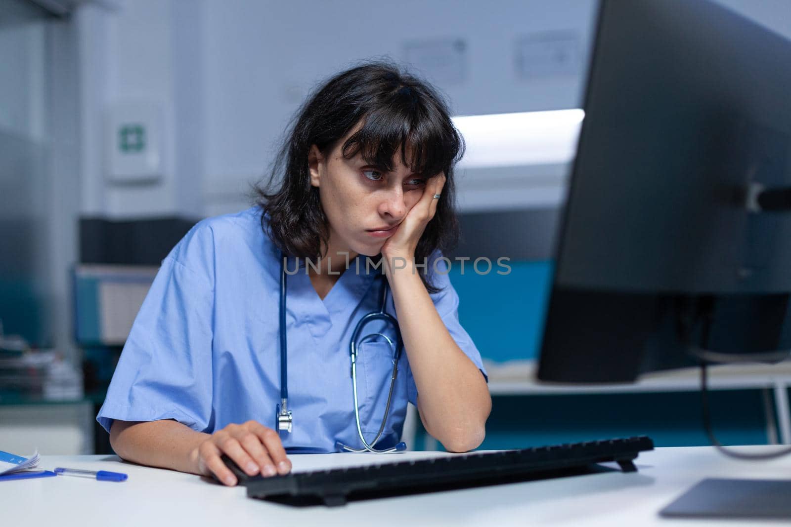 Medical specialist falling asleep at desk and using computer, working late at night. Woman assistant feeling burnout and exhaustion after doing overtime work on monitor for healthcare