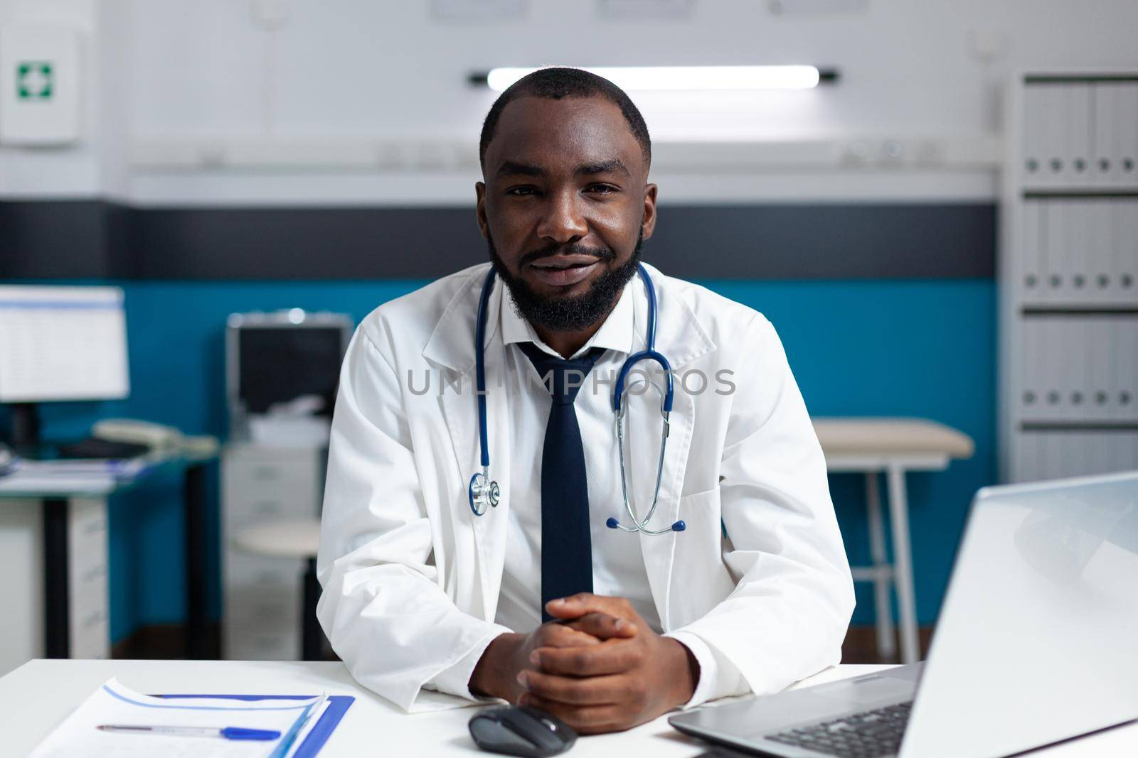 Portrait of african american practitioner doctor working in hospital office by DCStudio