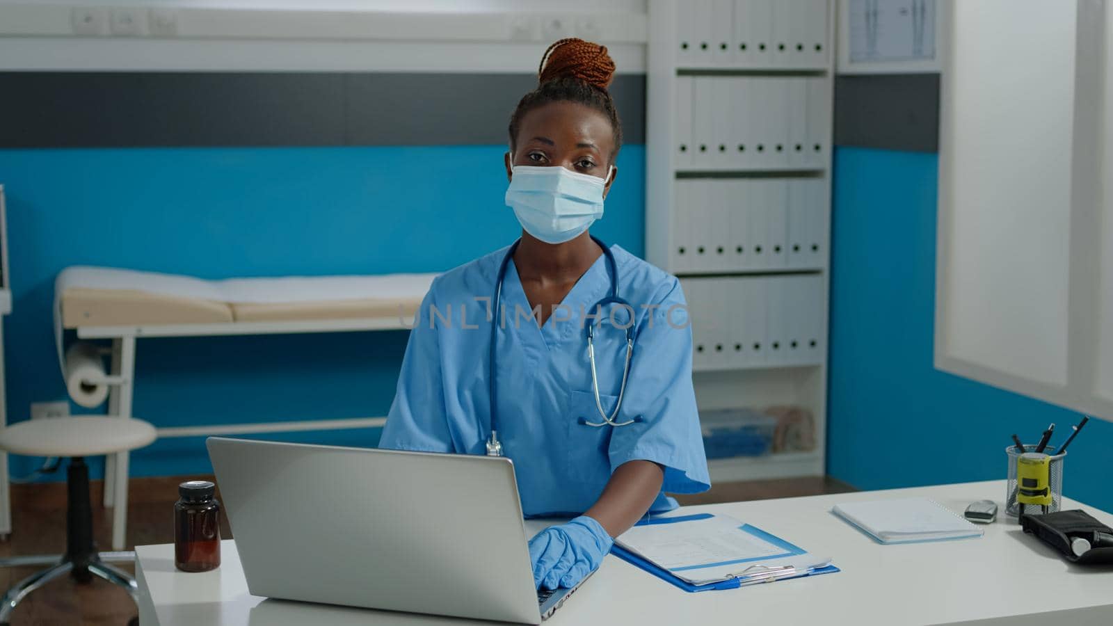 Portrait of woman nurse sitting at desk and using laptop by DCStudio