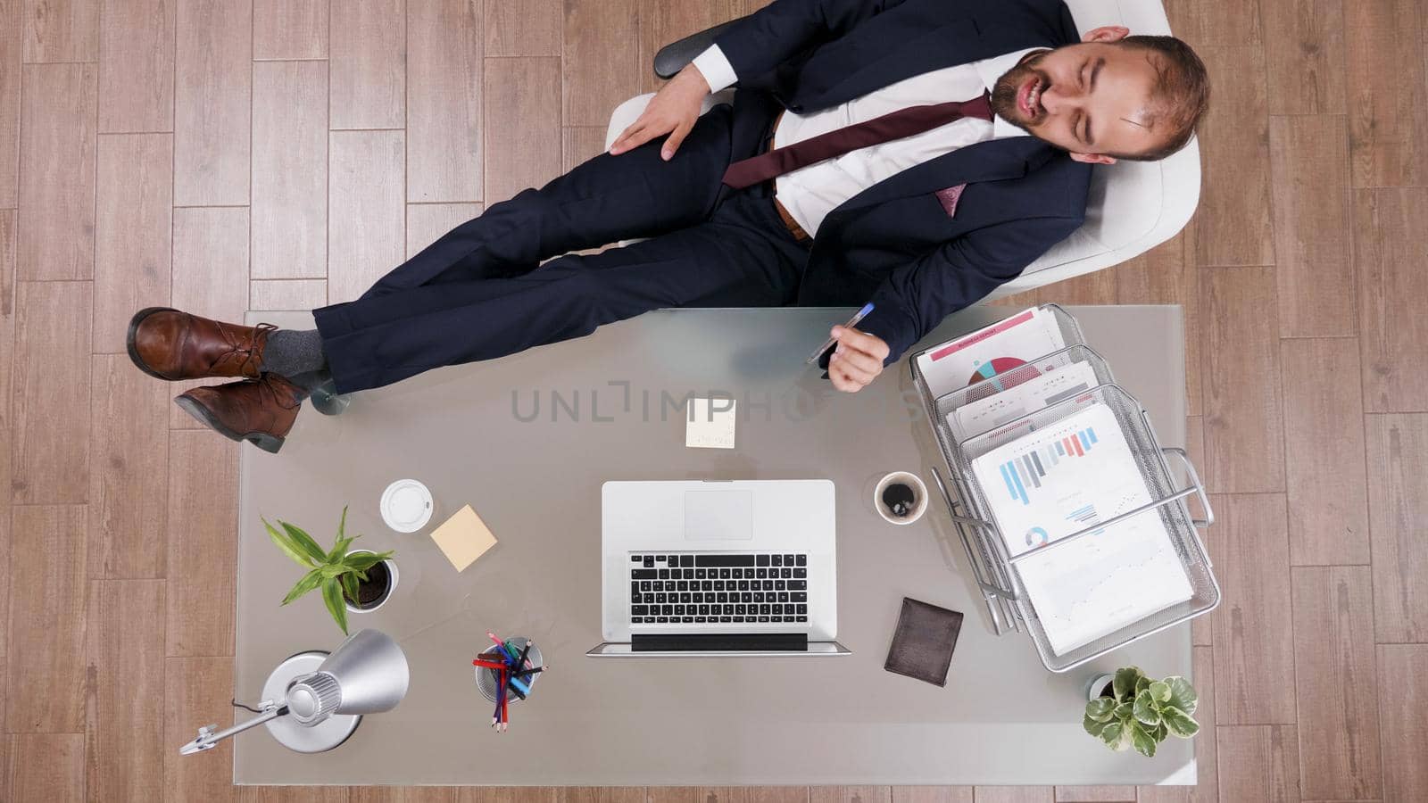 Top view of successful businessman in suit standing with his feet on the desk brainstorming company investments ideas. Executive manager working at business strategy in startup corporate office