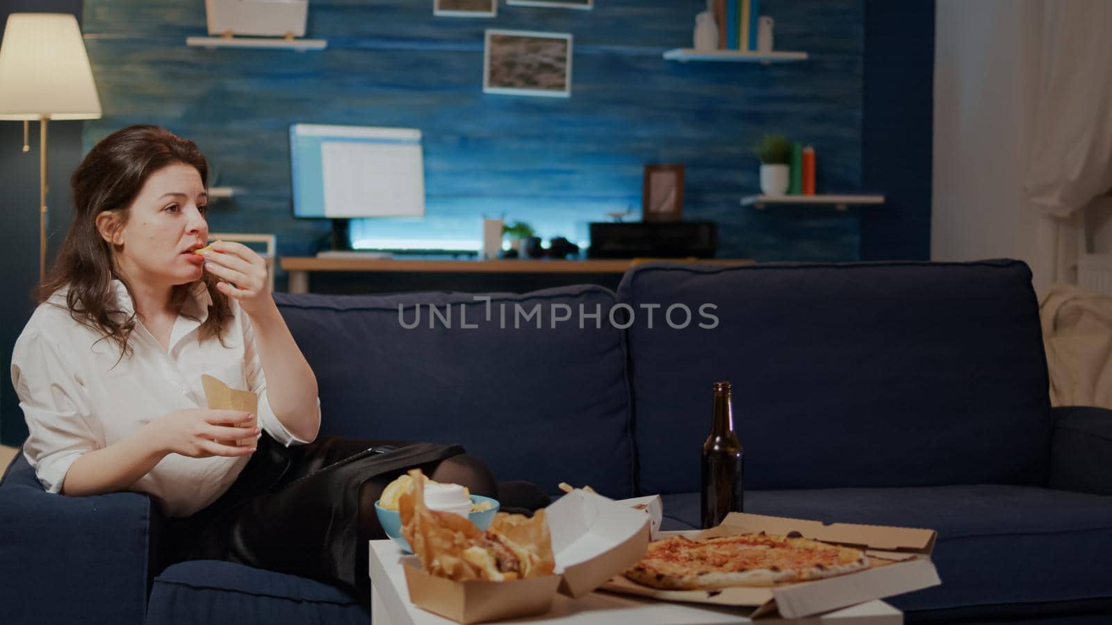 Woman relaxing on couch with takeaway food at home by DCStudio