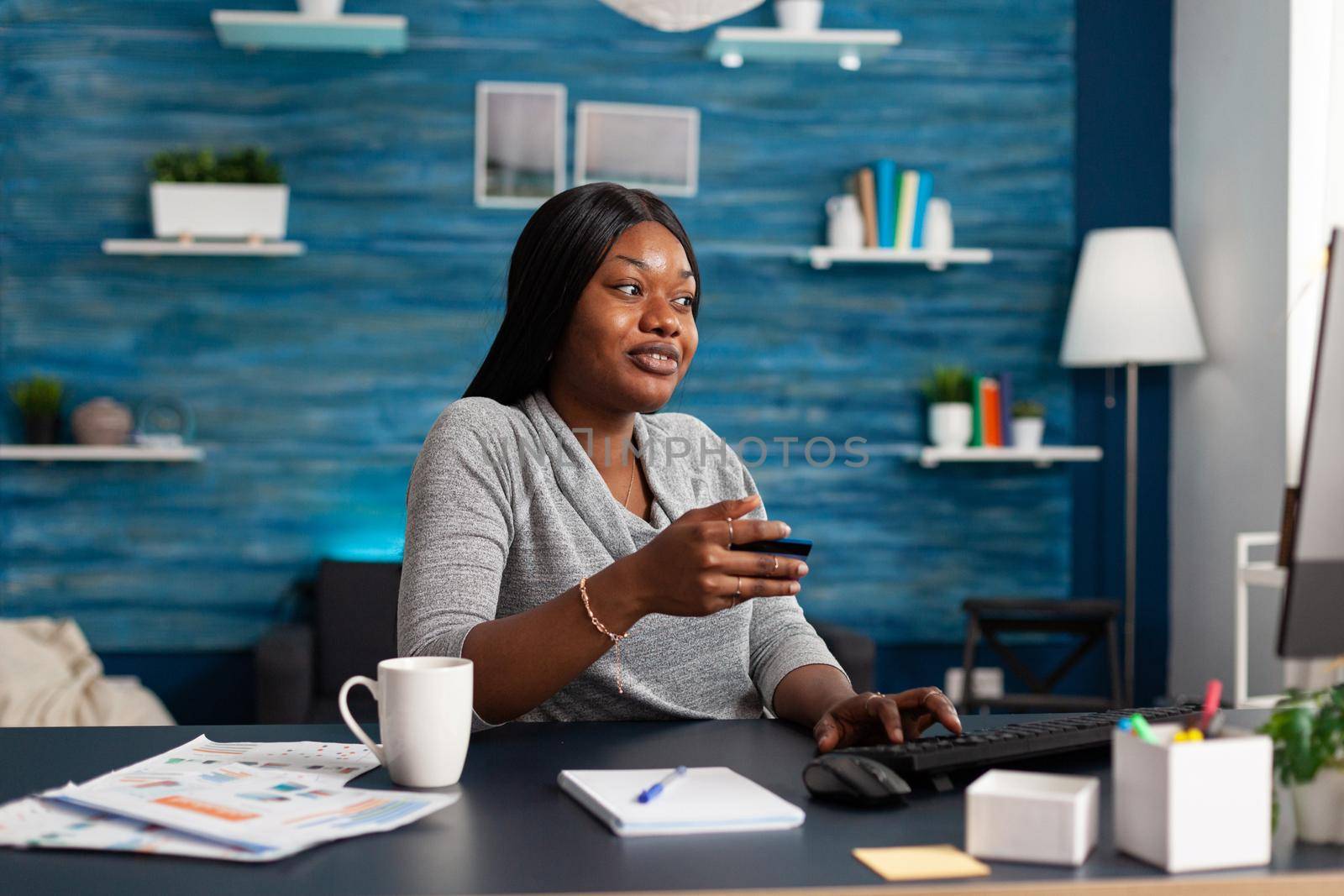 Black student paying online sale shopping holding economy credit card in hands by DCStudio