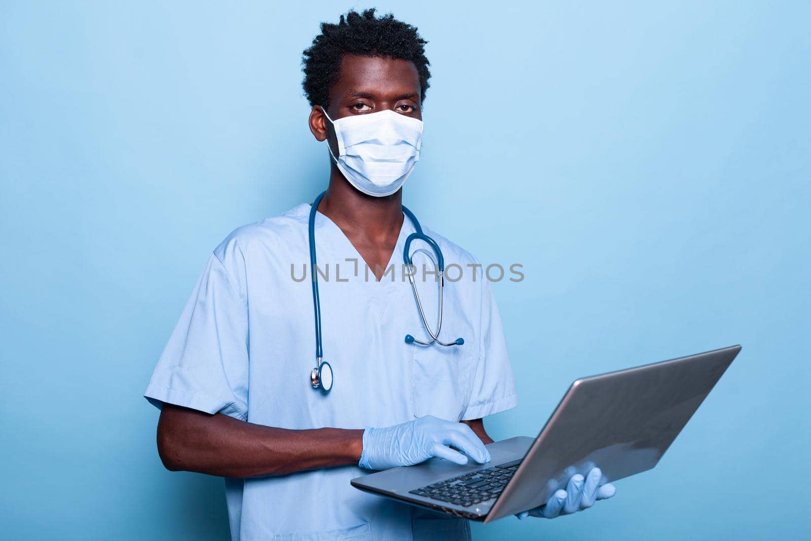 Healthcare assistant with laptop in hand wearing face mask by DCStudio