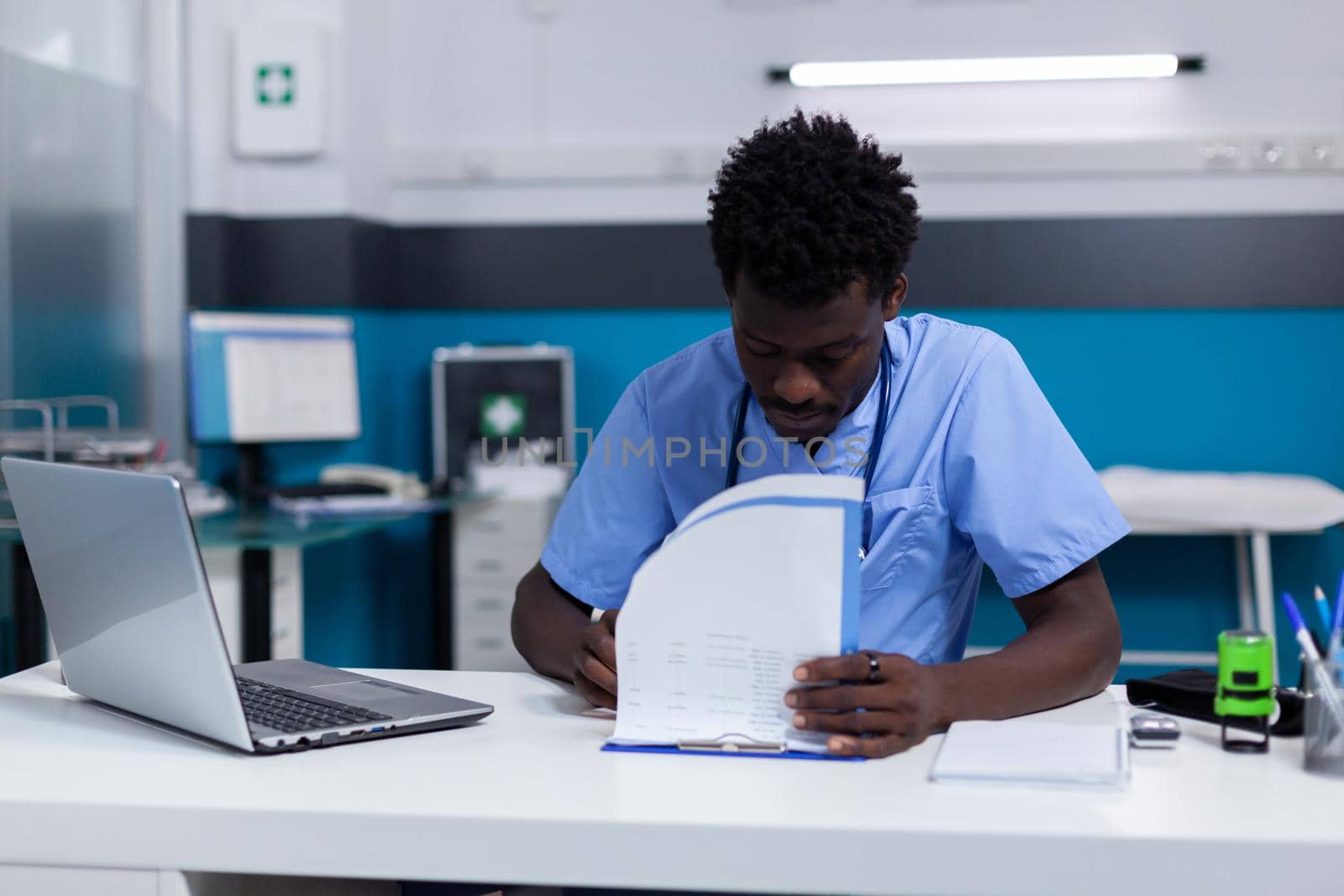 African american man nurse sitting at white desk in cabinet by DCStudio