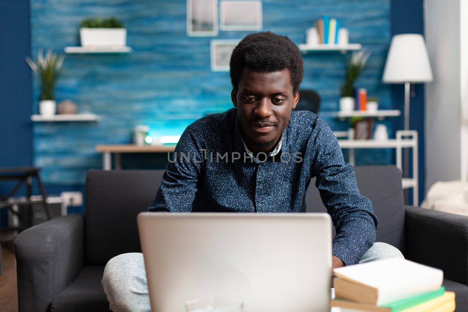 African american worker on video call conference from living room, talking on online internet connection using laptop. Working from home black man operating virtual modern technology