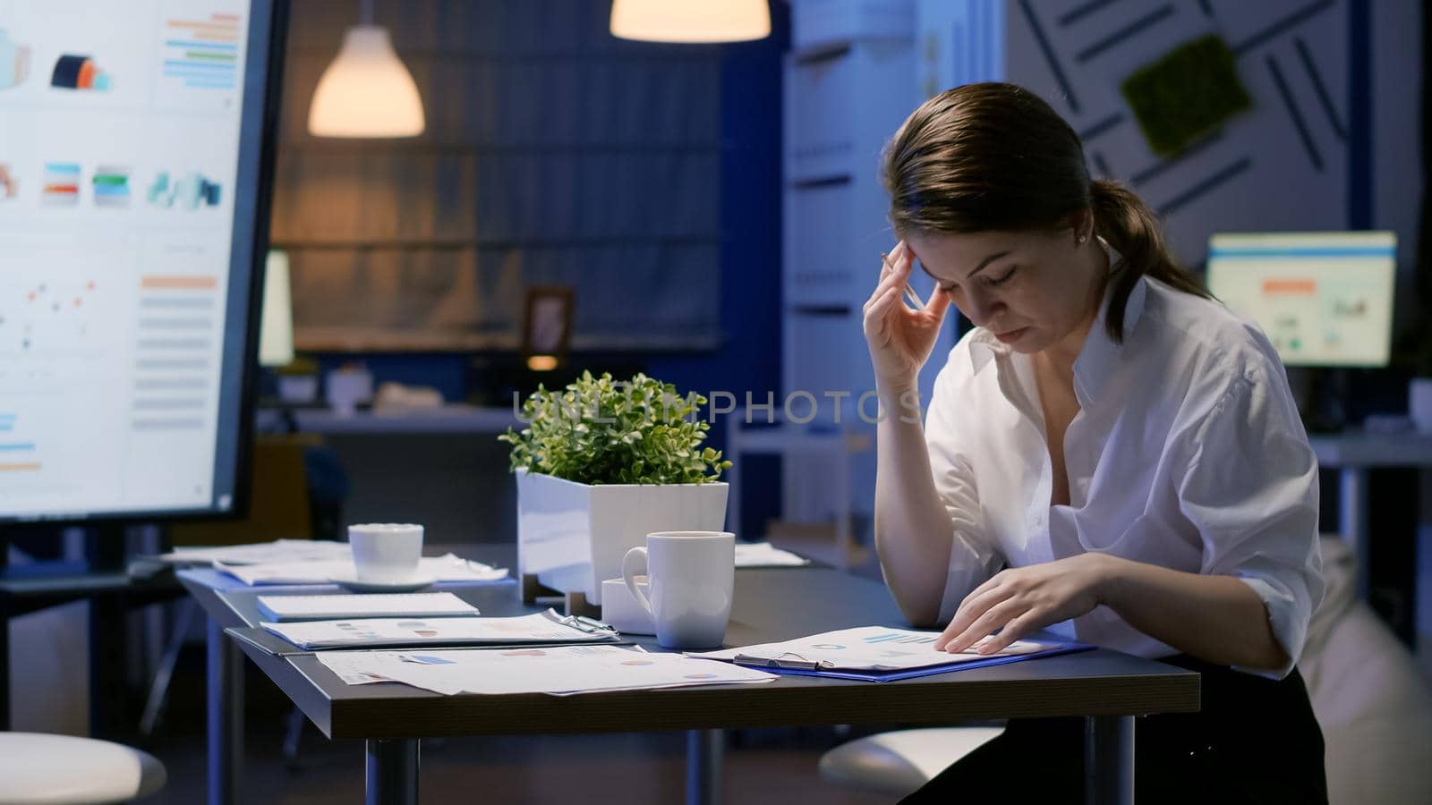 Entrepreneur woman hardworking in office meeting room analyzing company documents looking at management presentation on monitor late at night. Manager analyzing marketing profit in evening, corporate deadline