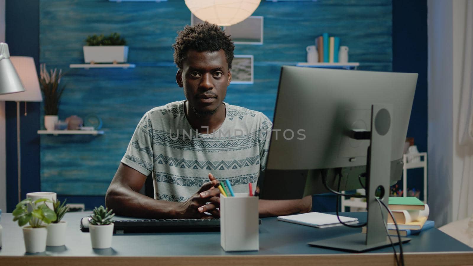 Adult of african ethnicity using computer for remote work and typing on keyboard. Businessman working from home with online technology and browsing internet. Person networking.