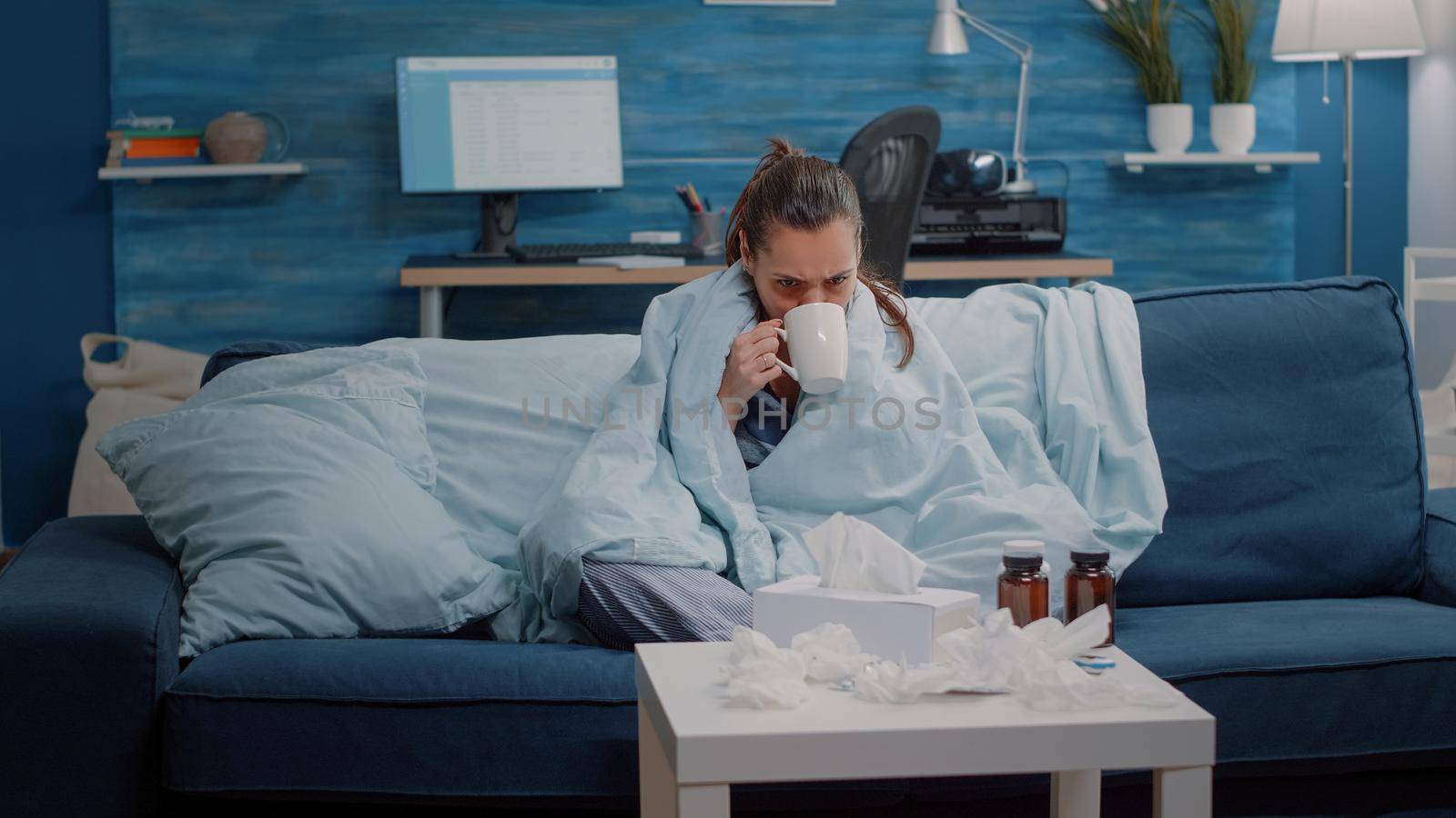 Adult shivering and feeling cold while using blanket and drinking tea for warmth. Woman with disease having chills and holding cup with hot beverage to cure coronavirus symptoms.