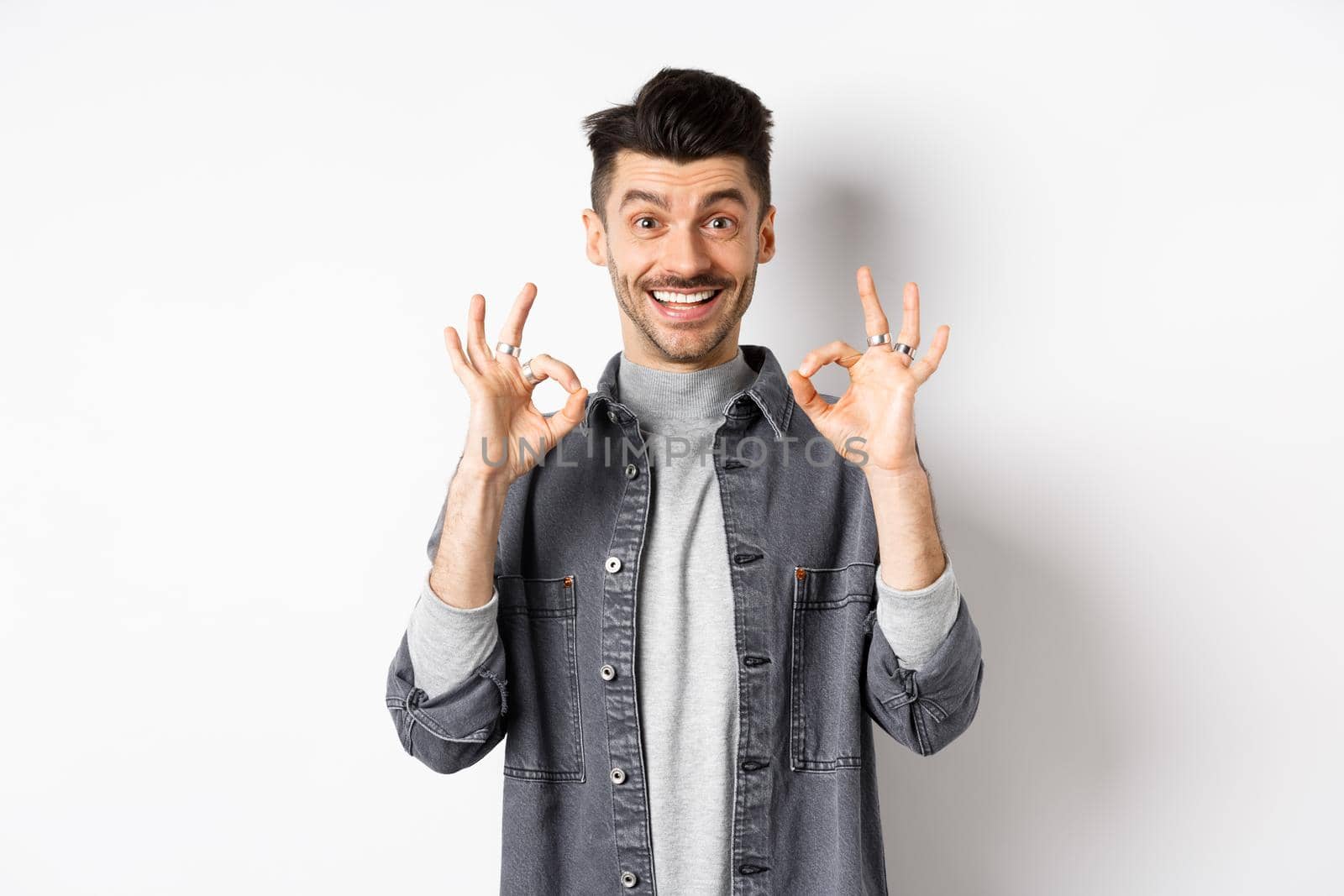 Happy guy say yes, smiling and showing okay signs, like good product, nod in approval and make satisfied face, praise excellent work, standing on white background.