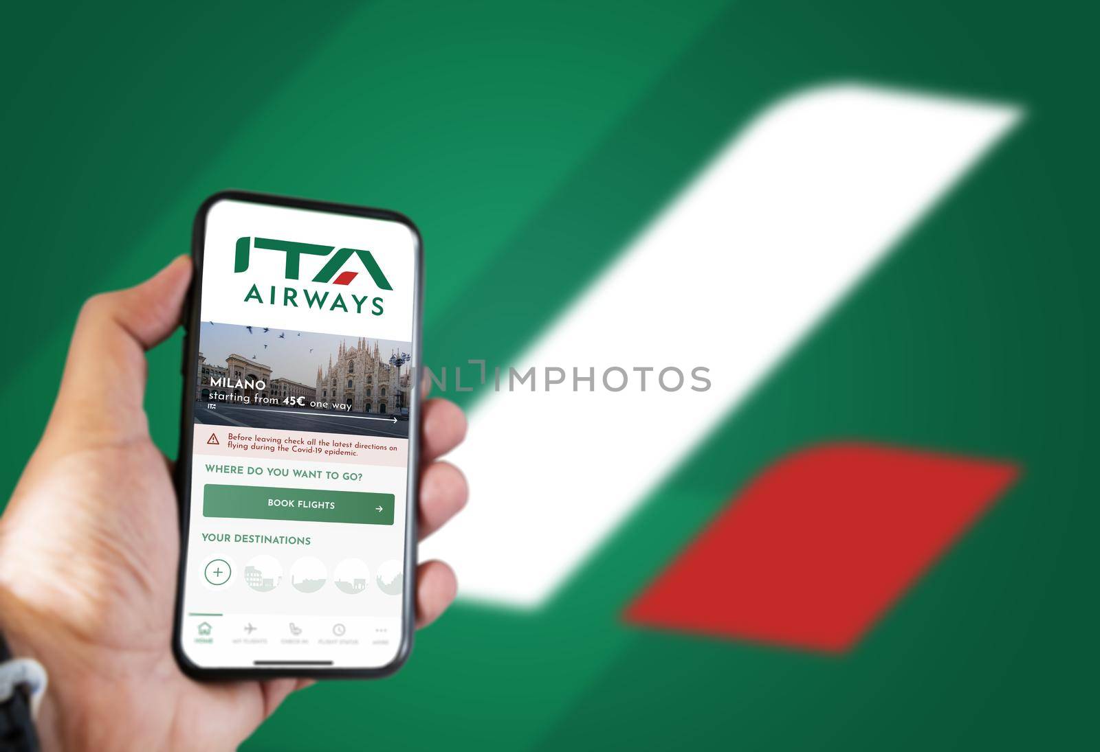Rome, IT, October 2021: hand holding a phone with the ITA Airways app on the screen and the logo blurred on a green background.ITA Airways is the new Italian flag carrier starting from 15 October 2021